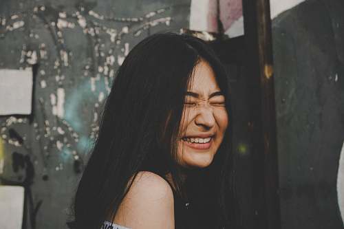 people smiling woman while closing her eyes photo human