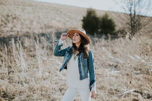 people woman holding her hat on grass field woman