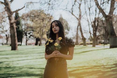 people woman holding yellow petaled flower during daytime human