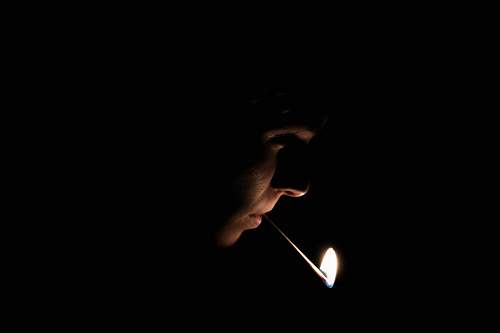 match man with lighted matchstick on his mouth lit match
