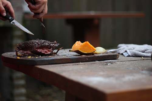 food person slicing a meat using knife and fork bbq