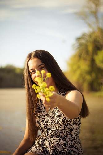 person woman holding yellow flower during daytime human