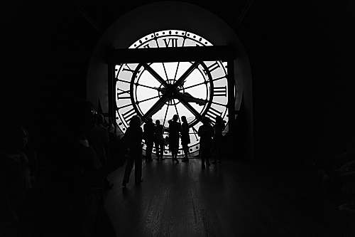 person silhouette of people across large clock human