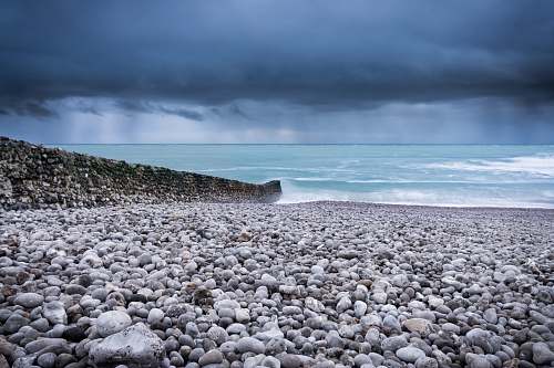 waves body of water across pebbles under dark sky pebble