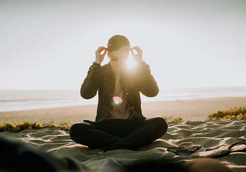 sport sitting man wearing black cap near body of water sports