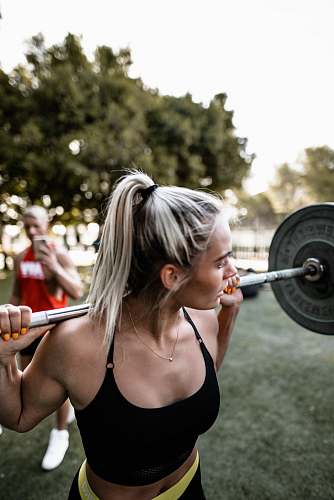 sport woman in black sports bra carrying barbell person