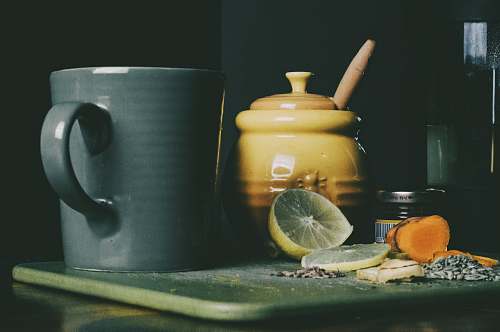 person beige ceramic jar beside grey ceramic pitcher and sliced lemon fruit cup