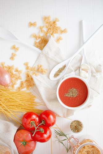 tomato four red tomatoes beside pasta and bowl flora