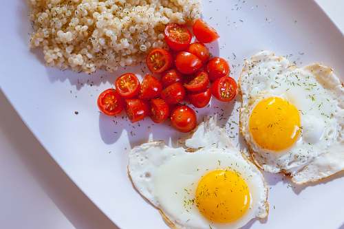 meal two sunny side eggs with sliced tomatoes on ceramic plate breakfast