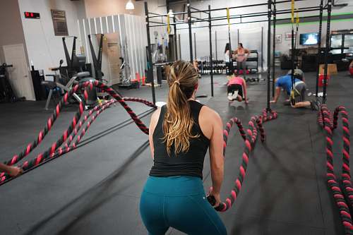 person woman in black top pulling rope working out