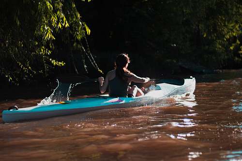 person woman paddling through river boat