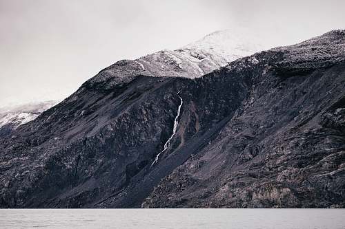 outdoors grayscale photo of body of water surrounded by mountain mountain