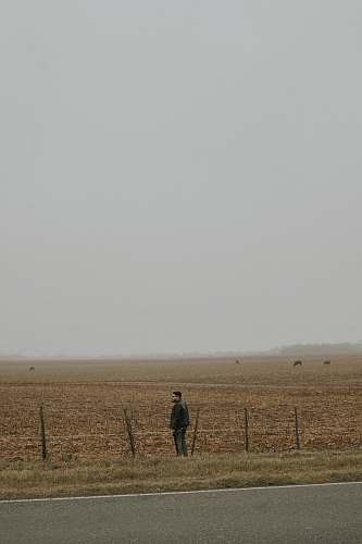 person man wearing black jacket standing on brown field human