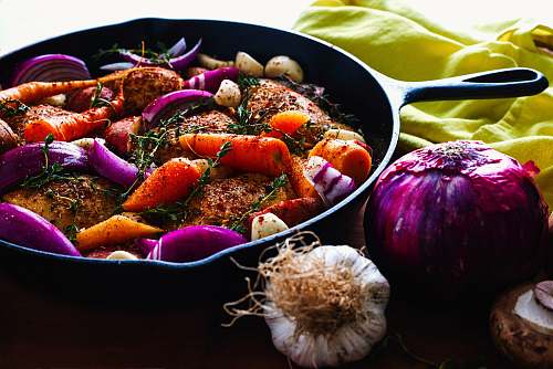 food carrots, garlic, onions, and herb spicing meat on skillet vegetable