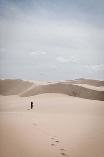 grey person waling on desert dune