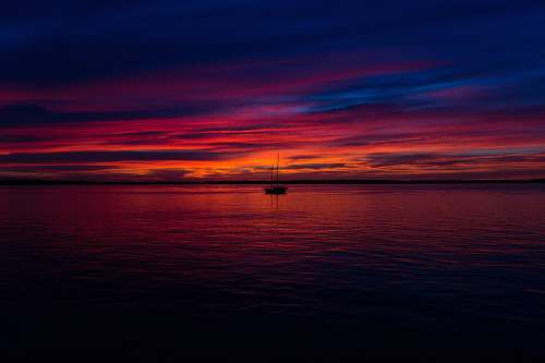 sky boat on body of water during golden time sunrise