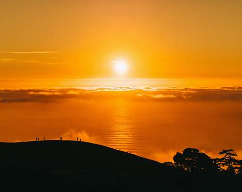 sky people on top of hill under white clouds golden hour photography sun