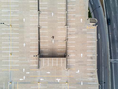 car person lying on gray concrete parking area in aerial photography drone