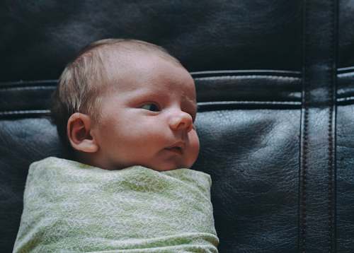 baby baby covered in green blanket on black leather surface newborn