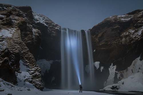 waterfall man standing in front of the waterfalls nature