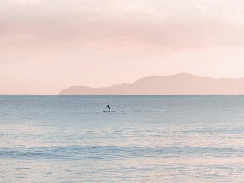 sea person paddle boarding during daytime pastel