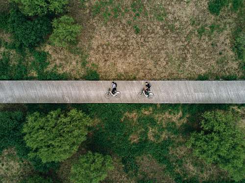 boardwalk aerial view photography of two person on road bicycle
