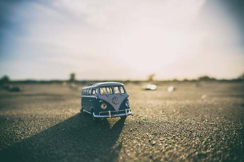 miniature shallow focus photography of white and teal die-cast Volkswagen Samba with sunlight vw bus