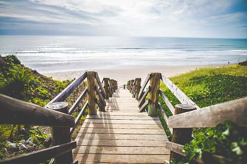 sea brown wooden walkway near beach during daytime bridge