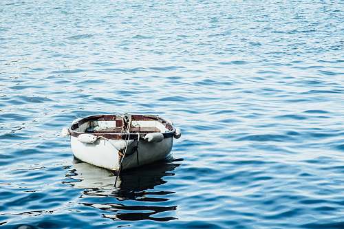water white wooden boat on body of water ocean