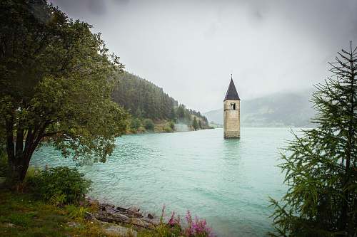 architecture concrete tower surrounded by water near land with trees tower
