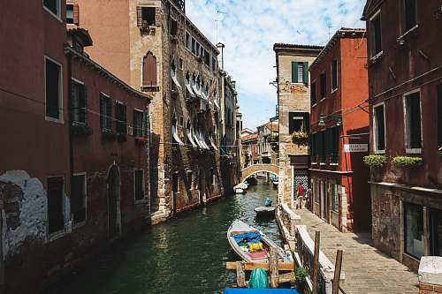 italy white motorboat on body of water between buildings at daytime boat