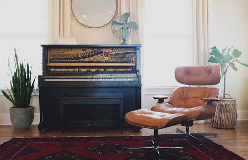 music black upright piano near brown leather padded chair interior