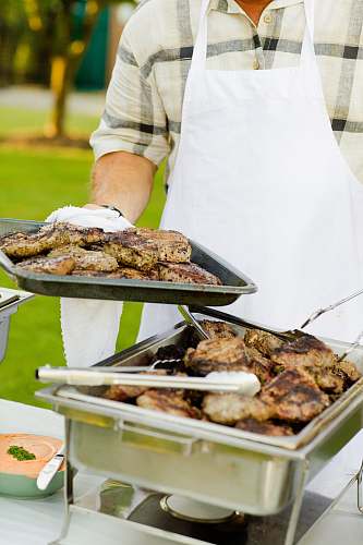 person person holding tray filled with grilled meat meal
