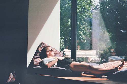 people man lying on cushion beside glass window person