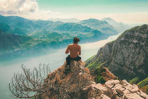 man man seating on top of cliff in front of mountains italy