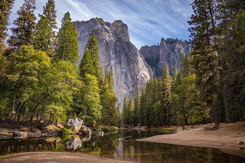 landscape calm body of water surrounded by trees near cliff mountain