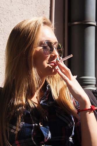person close-up photography of woman holding cigarette stick during daytime human