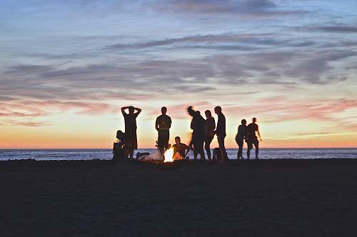 sunset group of people setting up campfire beach