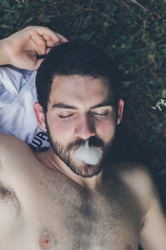 person man lying on grass field while smoking human