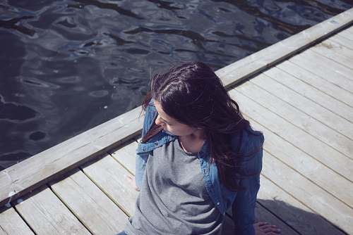 person woman in grey top seating on dock during daytime human