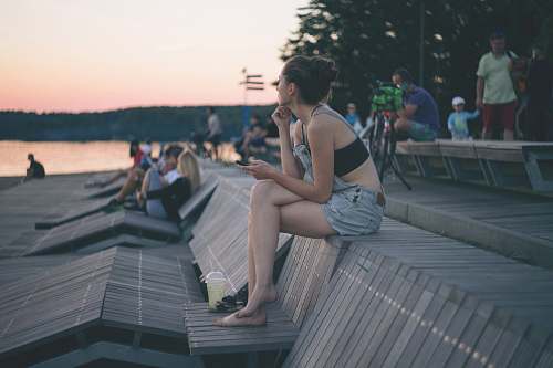 person woman sitting on top of wooden bench near people and beach human
