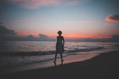 person woman standing on the seashore during golden hour human