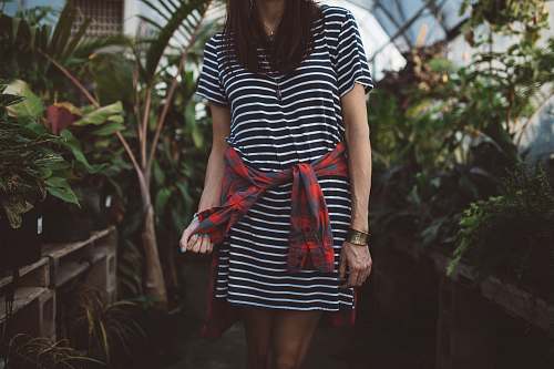 person woman wearing black and white striped dress standing in isle near green plants plant