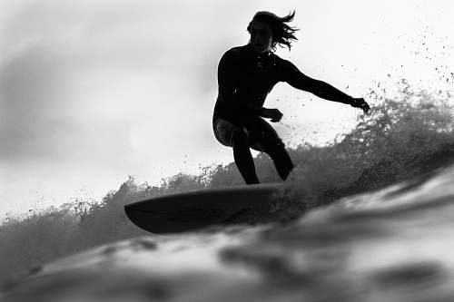 black-and-white grayscale photo of man riding a surfboard people
