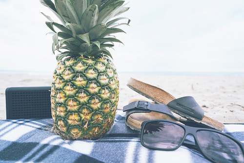 food green and yellow pineapple besides black slide slippers and sunglasses fruit
