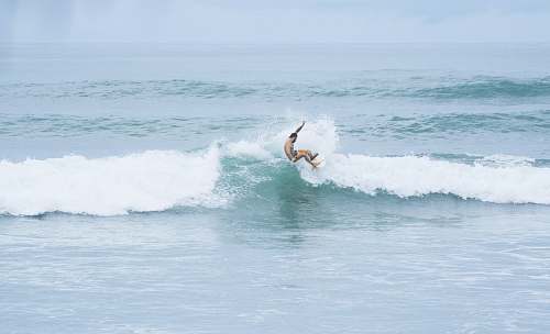 ocean man riding a surfboard facing the waves on the ocean surf