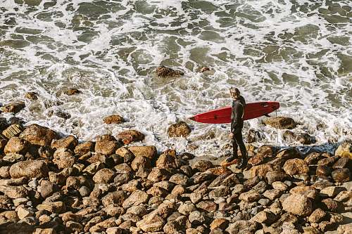 water person holding surfboard near seashore during daytime ocean