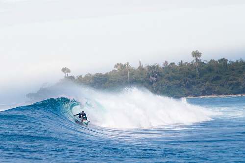 water man surfing on big waves under white sky sea