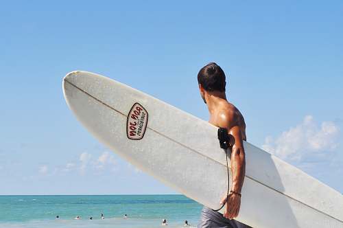 male topless man carrying white surfboard in beach during daytime florida