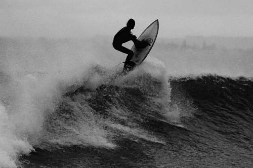 ocean grayscale photo of a man surfing black-and-white